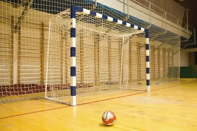 Bramka i piłka na parkiecie hali sportowej